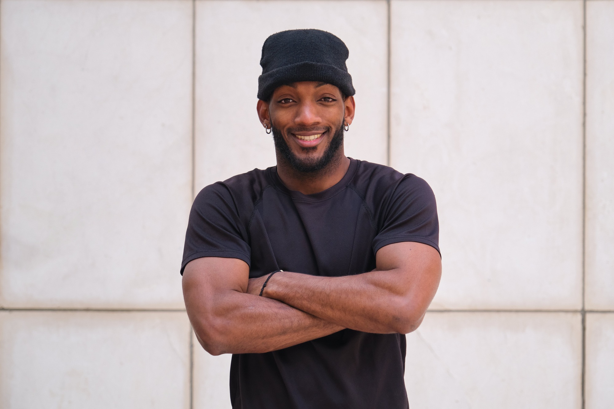 Confident male athlete smiling with folded arms